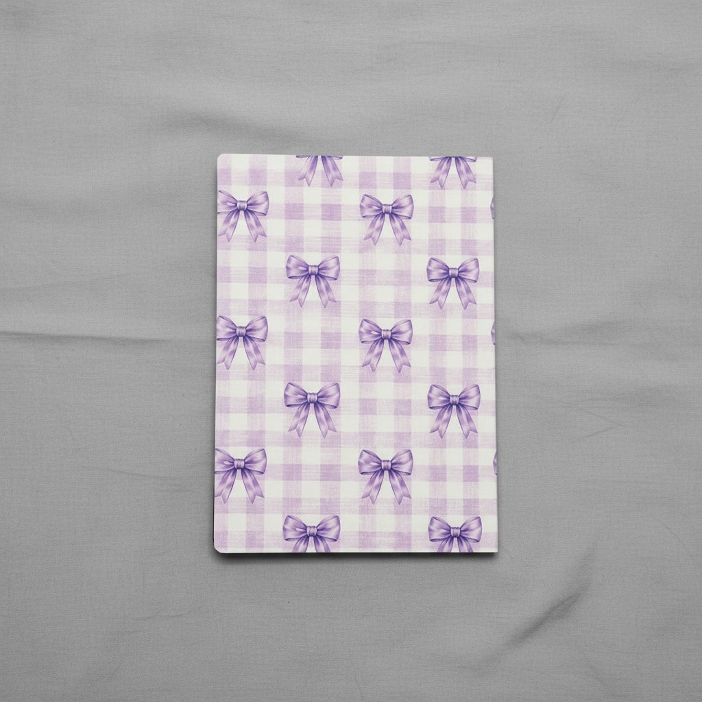 Titch of Everything hardcover journal with a purple gingham pattern and delicate bow illustrations on a grey background.