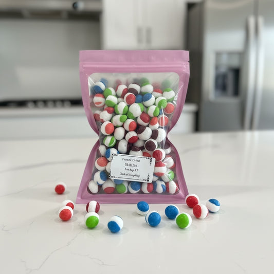 Titch of Everything freeze-dried Skittles in a resealable pink pouch with colorful crunchy candy pieces on a counter.